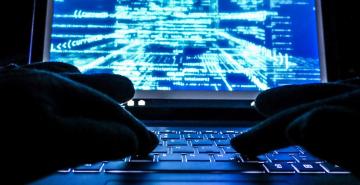 Cybercriminal with hands in gloves hacking into a system